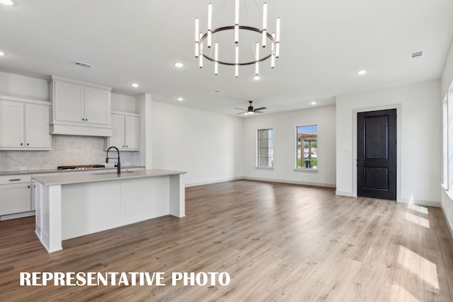 kitchen featuring white cabinetry, sink, a center island with sink, and backsplash