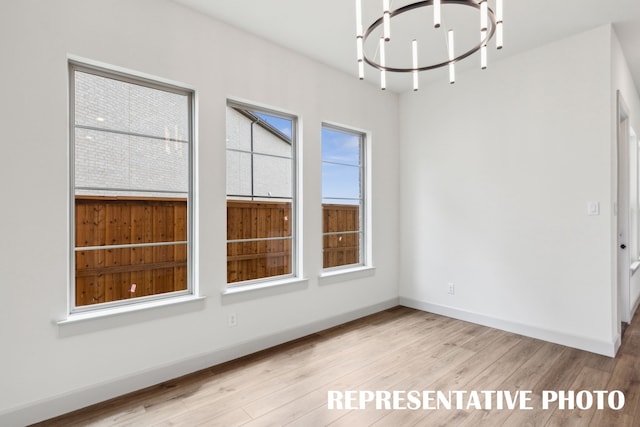 unfurnished dining area featuring an inviting chandelier and light wood-type flooring