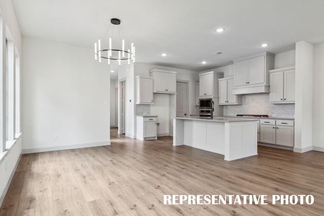 kitchen with white cabinetry, pendant lighting, stainless steel appliances, and an island with sink