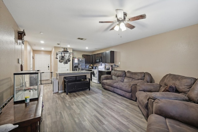 living room with ceiling fan and light hardwood / wood-style flooring