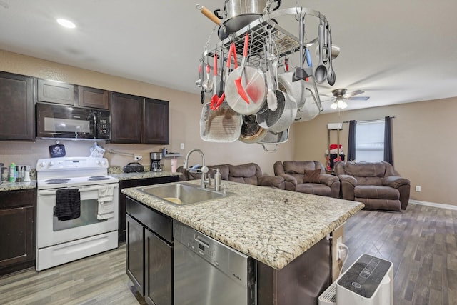 kitchen featuring an island with sink, electric range, dishwasher, dark brown cabinetry, and sink