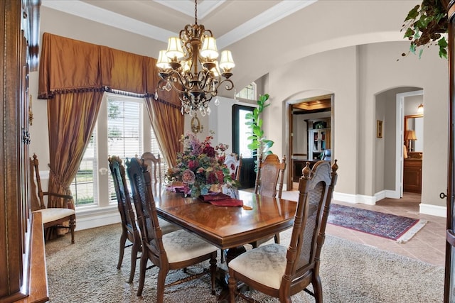 dining area with a chandelier, crown molding, a raised ceiling, and tile patterned flooring