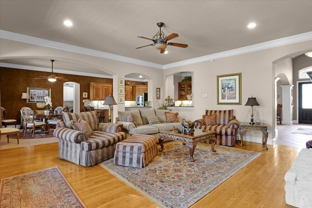 living room with ceiling fan, ornamental molding, and light hardwood / wood-style floors