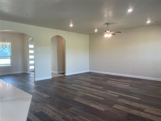 unfurnished room featuring ceiling fan with notable chandelier and dark hardwood / wood-style floors