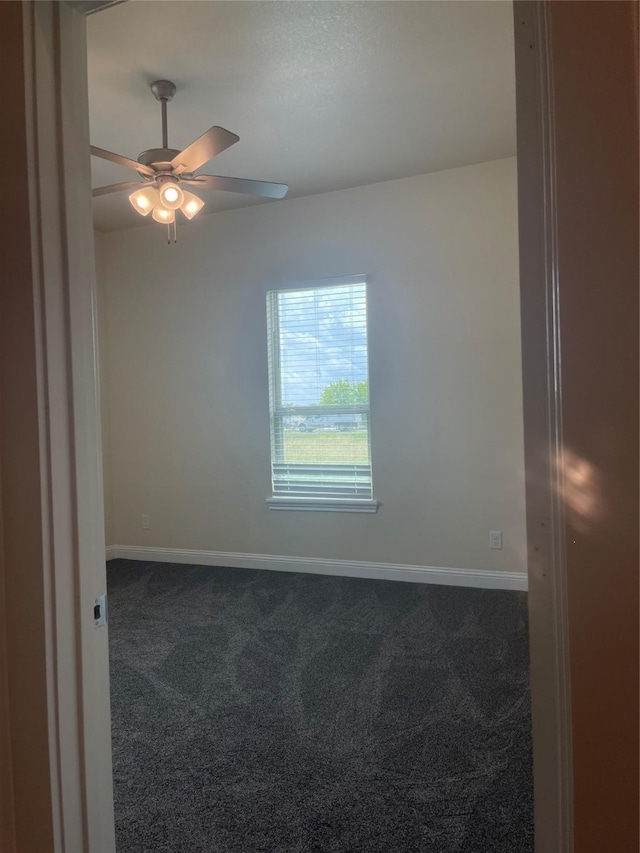 spare room featuring dark carpet and ceiling fan