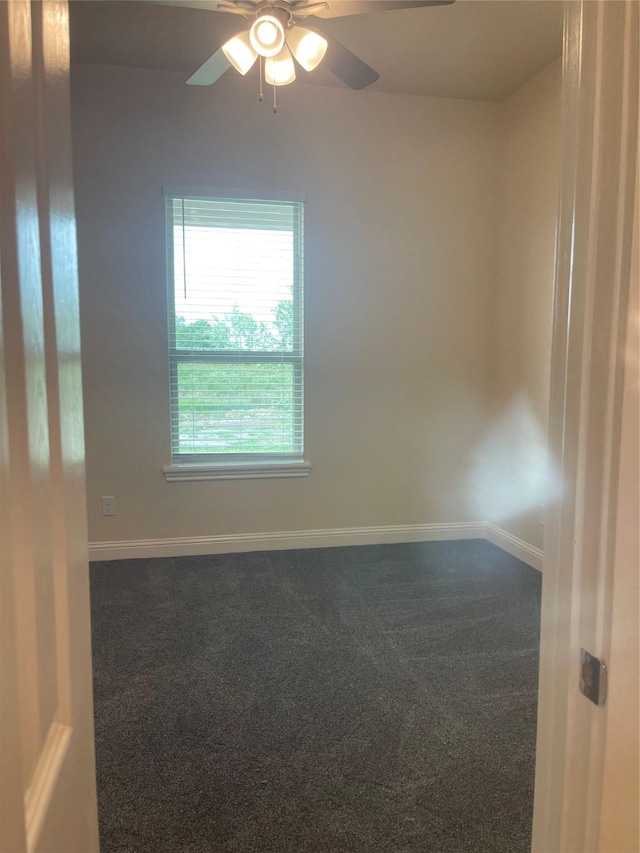 spare room with ceiling fan and dark carpet