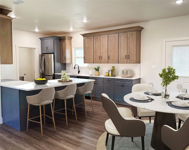 kitchen with gray cabinets, dark wood-type flooring, stainless steel refrigerator with ice dispenser, sink, and tasteful backsplash