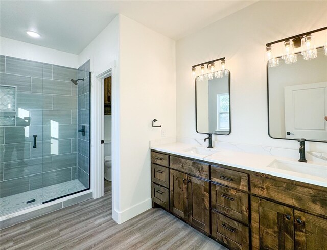 bathroom with toilet, hardwood / wood-style flooring, walk in shower, and vanity