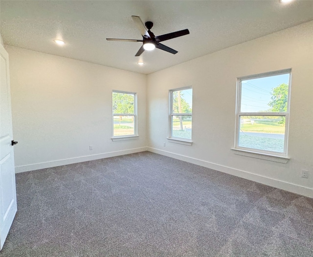 spare room with ceiling fan and dark colored carpet