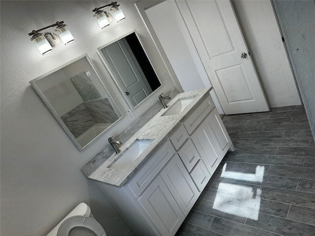 bathroom with tile patterned floors, toilet, and dual bowl vanity