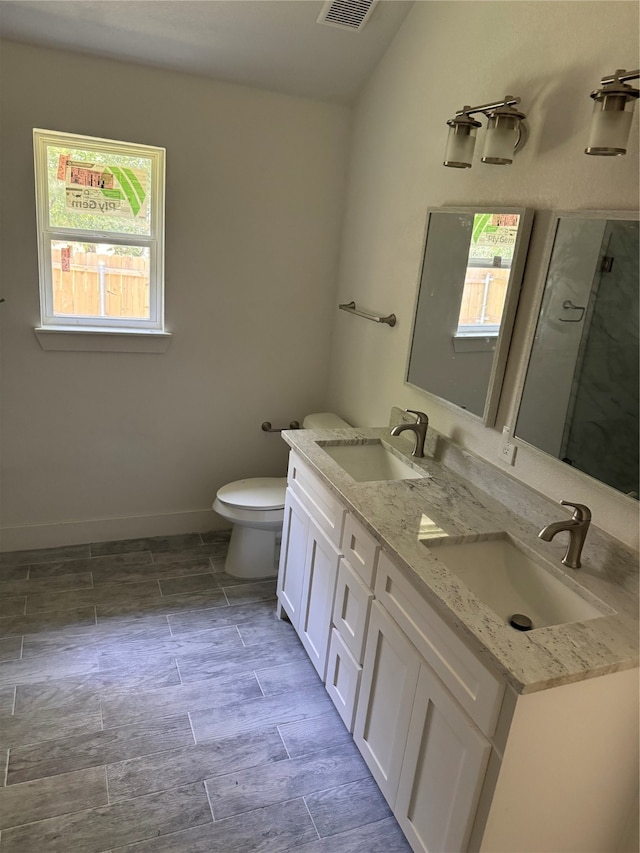 bathroom with tile patterned floors, dual bowl vanity, toilet, and a healthy amount of sunlight