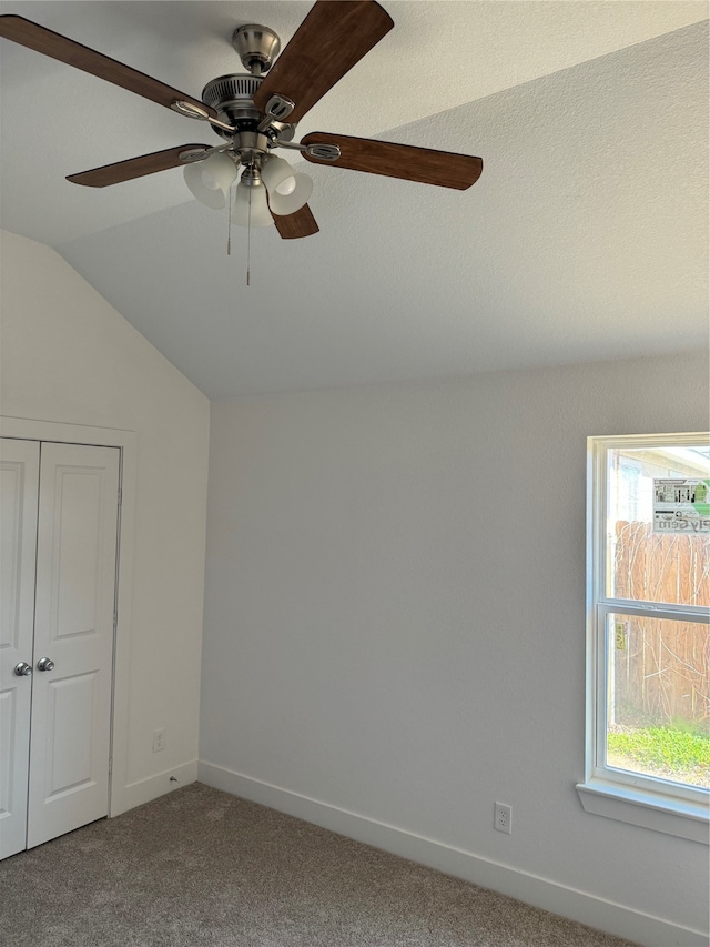 unfurnished bedroom with a closet, carpet, lofted ceiling, and ceiling fan