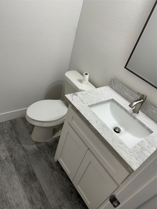 bathroom featuring hardwood / wood-style flooring, toilet, and vanity