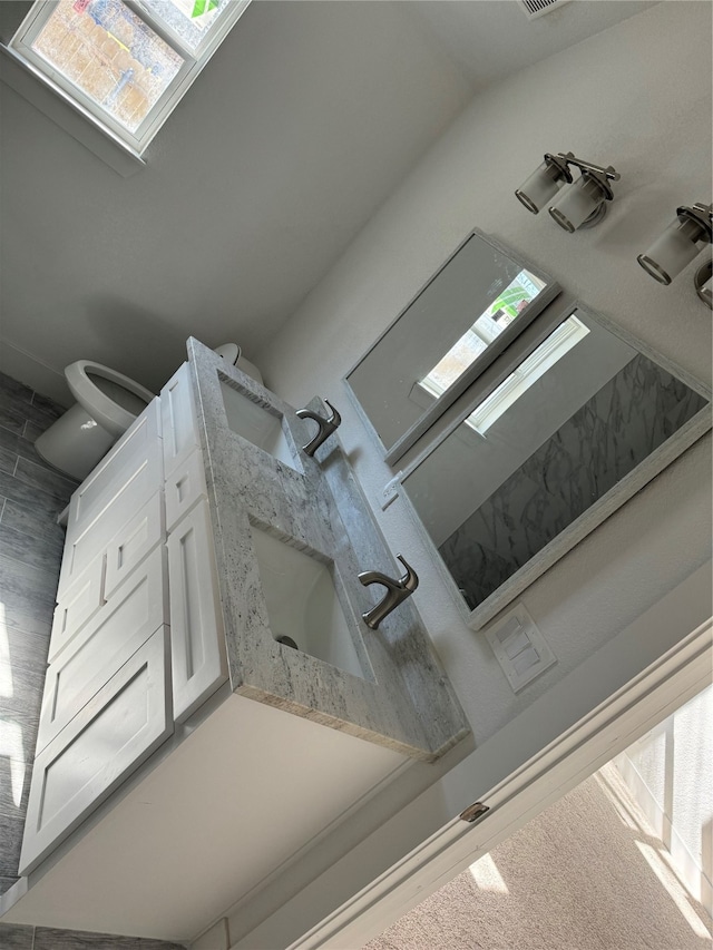 bathroom featuring vanity, toilet, tile patterned floors, and lofted ceiling