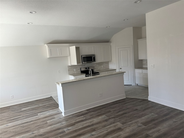 kitchen with lofted ceiling, white cabinets, backsplash, stainless steel appliances, and hardwood / wood-style floors