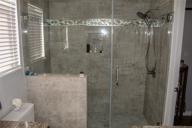 bathroom with a shower with door and toilet