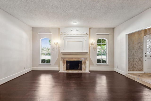 unfurnished living room with dark hardwood / wood-style floors, plenty of natural light, a premium fireplace, and a textured ceiling