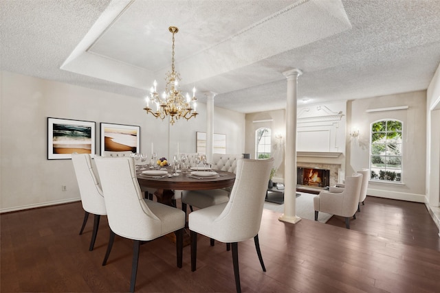 dining room with an inviting chandelier, dark hardwood / wood-style floors, decorative columns, and a raised ceiling