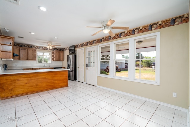 kitchen featuring sink, stainless steel refrigerator, ceiling fan, light tile patterned flooring, and decorative backsplash