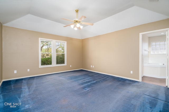 carpeted spare room featuring ceiling fan, lofted ceiling, and a tray ceiling