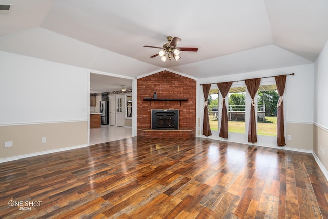 unfurnished living room featuring lofted ceiling, a brick fireplace, wood-type flooring, and ceiling fan