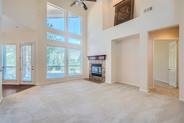 unfurnished living room featuring a high ceiling, light carpet, a fireplace, and ceiling fan