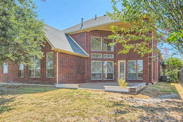 rear view of property featuring a lawn, cooling unit, and a patio area