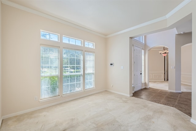 carpeted empty room with an inviting chandelier and ornamental molding