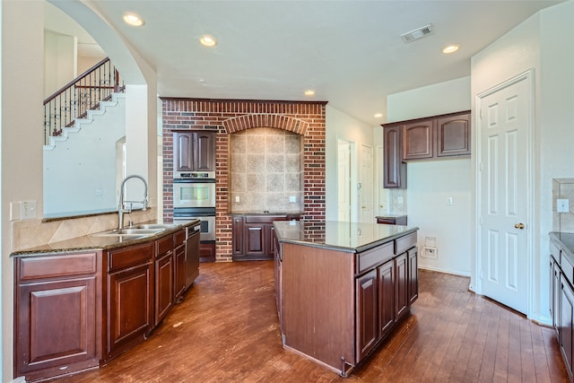 kitchen featuring sink, double oven, a center island, and backsplash