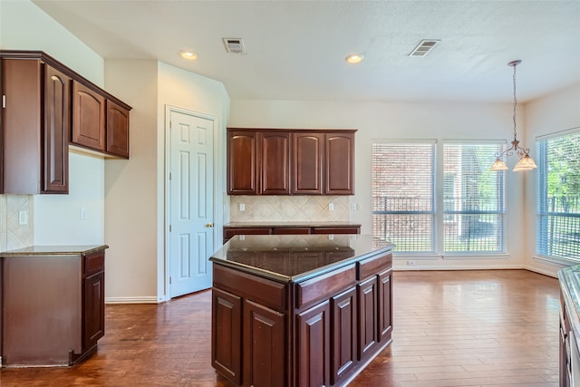 kitchen with a notable chandelier, pendant lighting, dark hardwood / wood-style floors, dark brown cabinets, and backsplash