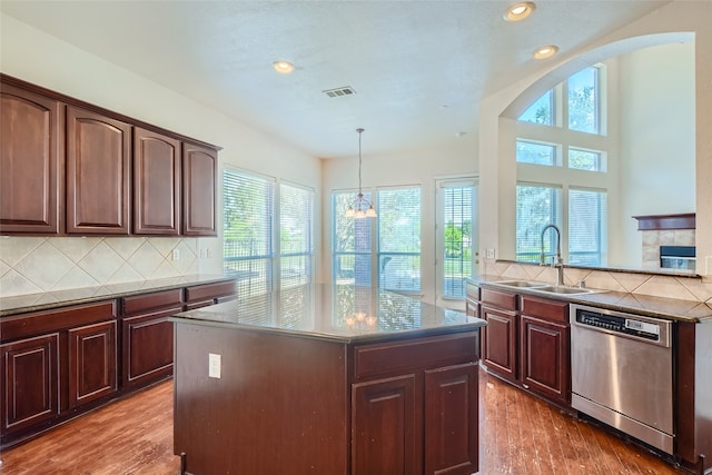 kitchen with sink, tasteful backsplash, stainless steel dishwasher, wood-type flooring, and a notable chandelier