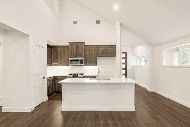 kitchen featuring stove, sink, high vaulted ceiling, dark hardwood / wood-style floors, and an island with sink