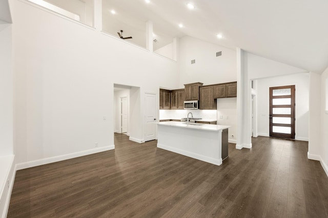 kitchen with dark hardwood / wood-style flooring, ceiling fan, sink, a high ceiling, and an island with sink