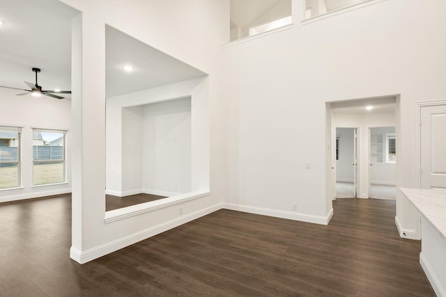 interior space featuring ceiling fan, a towering ceiling, and dark wood-type flooring