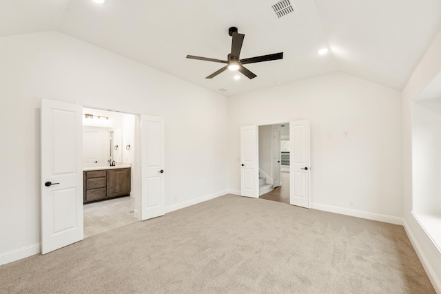 unfurnished bedroom with light carpet, vaulted ceiling, ensuite bath, and ceiling fan