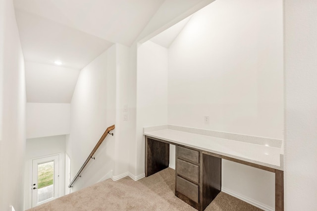 unfurnished office featuring light colored carpet and vaulted ceiling