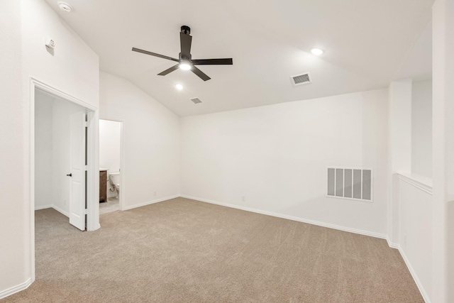 spare room featuring light carpet, vaulted ceiling, and ceiling fan