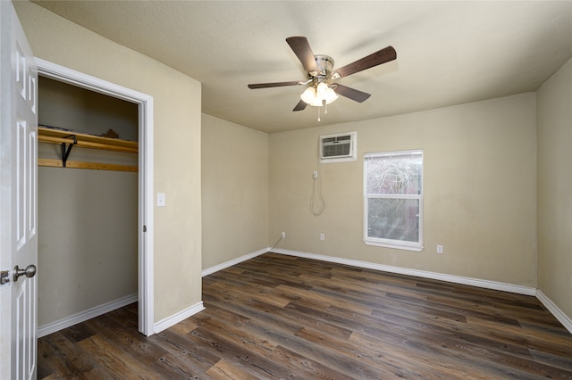 unfurnished bedroom featuring a closet, an AC wall unit, ceiling fan, and dark wood-type flooring