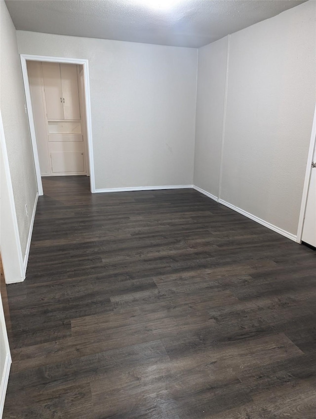 empty room with a textured ceiling and dark hardwood / wood-style floors