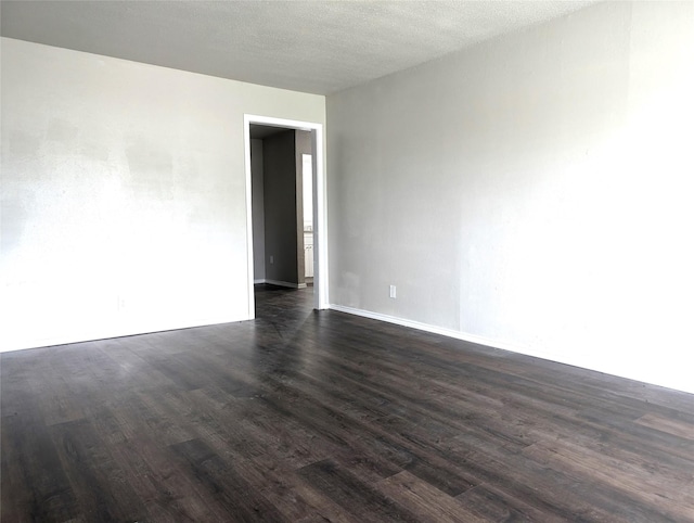 spare room with a textured ceiling and dark hardwood / wood-style floors