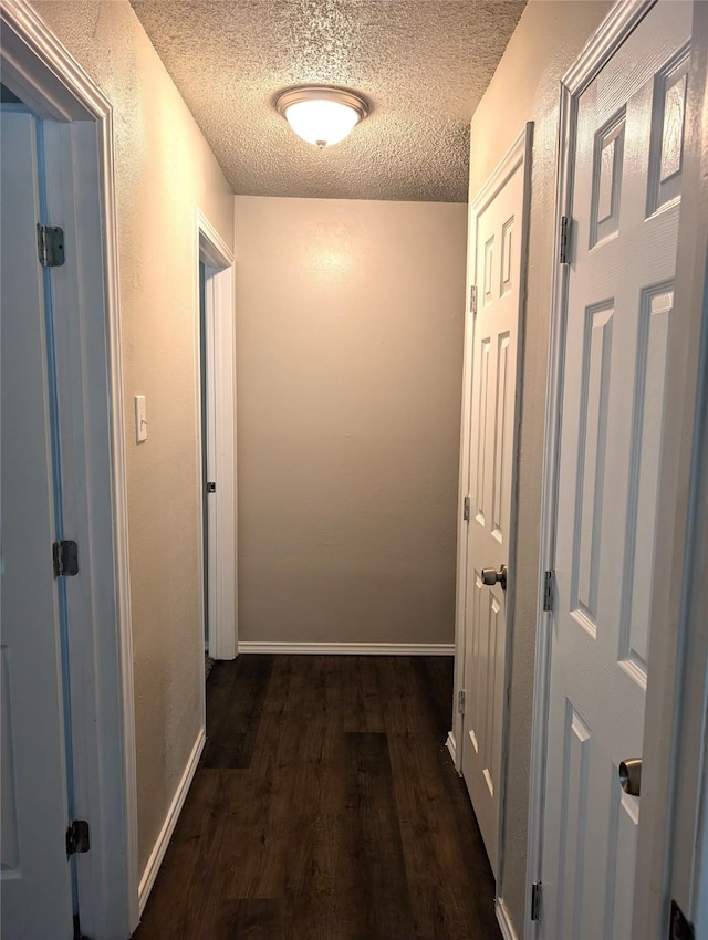 hallway with a textured ceiling and dark hardwood / wood-style flooring