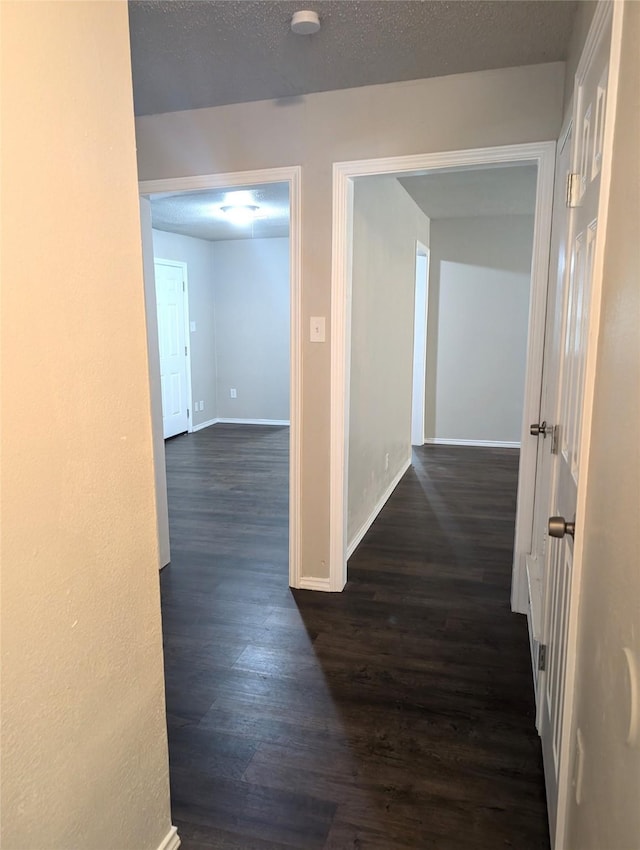 hallway featuring a textured ceiling and dark wood-type flooring