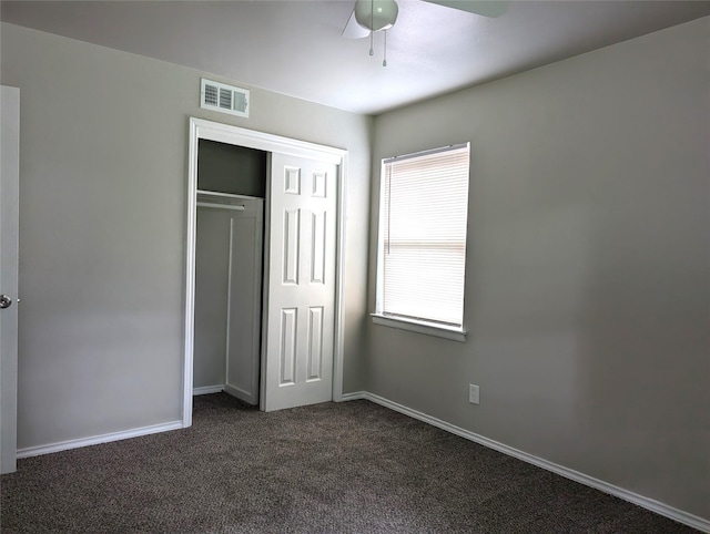 unfurnished bedroom with ceiling fan, a closet, and dark colored carpet