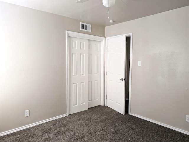 unfurnished bedroom featuring ceiling fan, a closet, and dark colored carpet