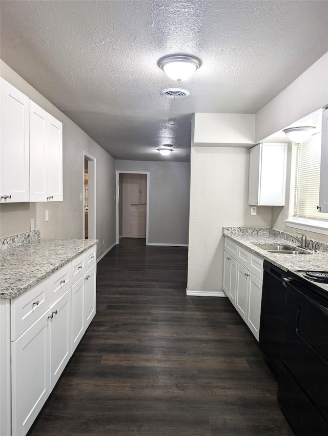 kitchen with light stone countertops, white cabinetry, black appliances, and sink