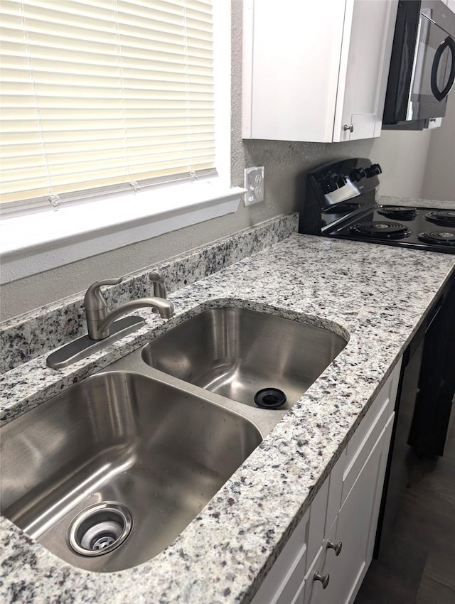 room details featuring light stone countertops, white cabinets, and sink