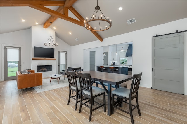 dining area with a fireplace, a healthy amount of sunlight, a barn door, and light wood-type flooring