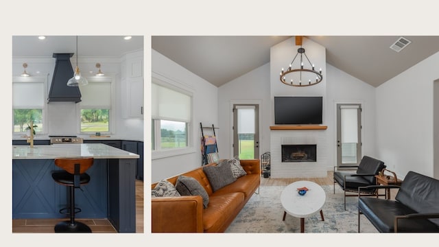 living room featuring lofted ceiling, light hardwood / wood-style flooring, a fireplace, and an inviting chandelier