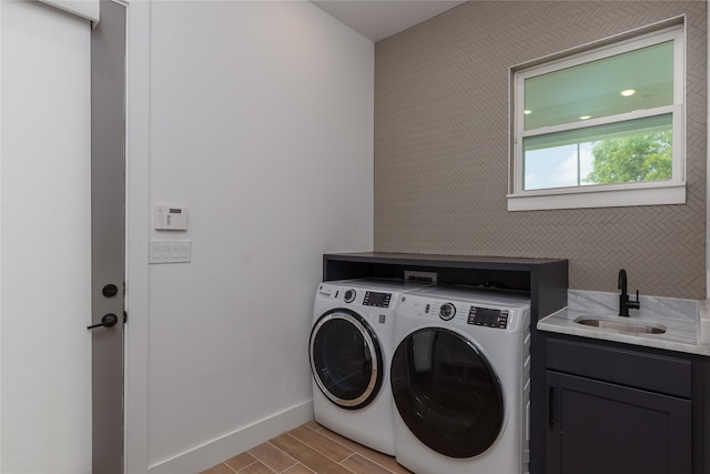 clothes washing area with sink, light hardwood / wood-style flooring, separate washer and dryer, and cabinets