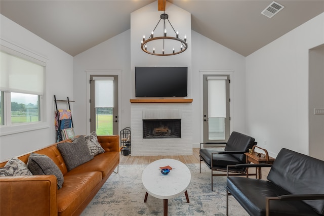 living room with a chandelier, vaulted ceiling, light wood-type flooring, and a fireplace